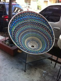 a large blue and green bowl sitting on top of a metal stand next to a parked car