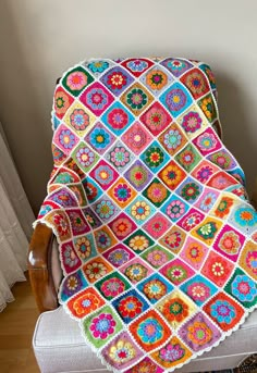 a crocheted granny blanket sitting on top of a chair next to a window