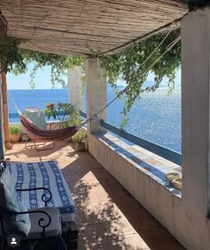 a hammock sitting on top of a patio next to the ocean