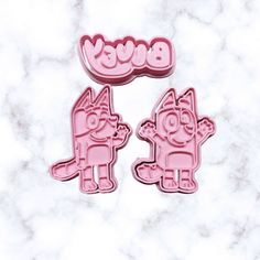 two pink pig shaped cookie cutters sitting on top of a marble counter