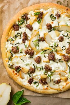 a pizza sitting on top of a piece of wax paper next to an apple slice