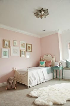 a bedroom with pink walls and pictures on the wall, including a small child's bed