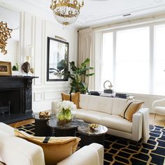 a living room filled with furniture and a chandelier hanging from the ceiling over a fire place