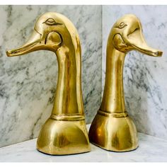 two golden ducks sitting on top of a marble counter