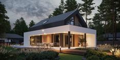 a modern house in the evening with lights on it's front porch and patio