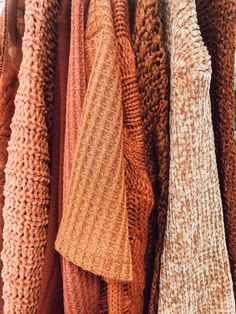 an assortment of sweaters hanging on a rack