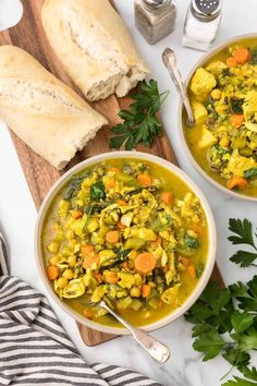 two bowls of vegetable soup with bread and parsley