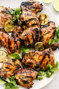 grilled chicken with lemons and herbs on a white plate