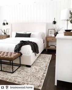 a white bed sitting on top of a wooden floor next to a dresser and lamp