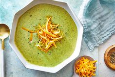 a bowl of broccoli soup with cheese on top and spoons next to it