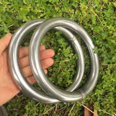 a hand is holding two metal rings in the grass