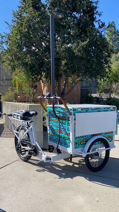 a bike with a cart attached to it parked in front of a pole on the sidewalk