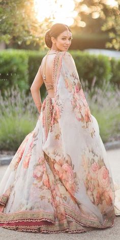 a woman in a floral dress is standing on the sidewalk with her back to the camera