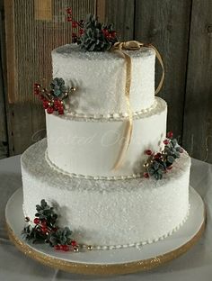 a three tiered wedding cake with pine cones on top