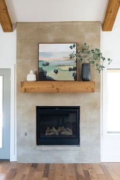 a living room with a fire place and painting on the fireplace mantel above it