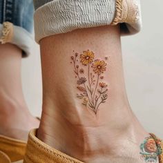 a woman's foot with daisies and bees tattoo on the side of her ankle