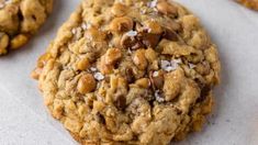 a cookie with nuts on top is sitting on a piece of parchment paper next to other cookies