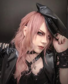 a woman with pink hair wearing a black hat and leather outfit, posing for the camera