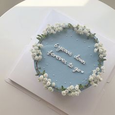 a blue cake decorated with white flowers and the words years down, forever to go