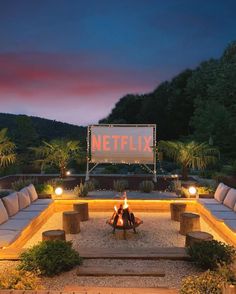 a fire pit surrounded by benches and seating in the middle of a garden at night