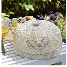 a large white doily covered cake sitting on top of a table next to flowers