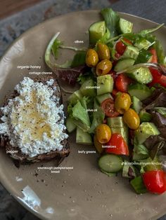 a white plate topped with a salad and toast next to a bowl of dressing on top of a table