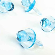 three blue glass cups sitting next to each other on a white surface with no one around them