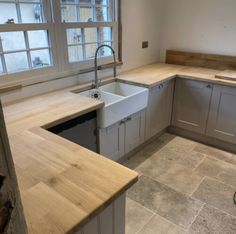 an empty kitchen with wooden counter tops and grey cabinets, including a sink in the center