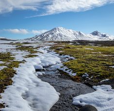 a snow covered field with mountains in the distance and rocks on the ground near by