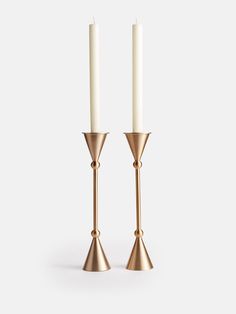 two brass candlesticks with one candle in the middle and one on each side