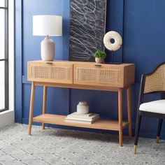 a wooden table with two drawers and a lamp on it next to a blue wall