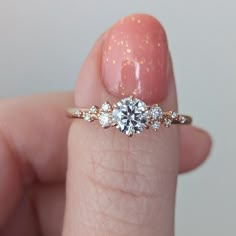 a close up of a person's hand holding a ring with three diamonds on it