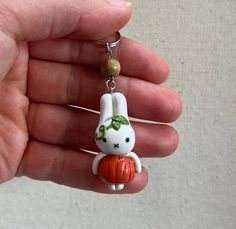 a hand holding a tiny keychain with a rabbit on it's back