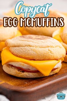 an egg muffin with cheese and bacon is on a cutting board next to some biscuits