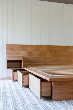 a wooden bed with two drawers underneath it