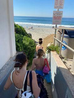 some people are sitting on the steps by the beach and looking out at the ocean