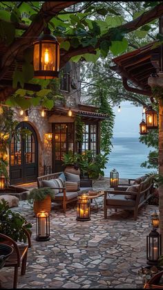 an outdoor living area with lanterns and chairs on the patio overlooking the water at dusk