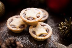 four small pastries sitting on top of a wooden table covered in powdered sugar