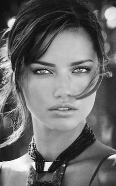 a close up of a person wearing a necklace and posing for a photo with trees in the background