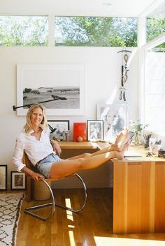 a woman sitting in a chair with her feet up on the desk and looking at the camera