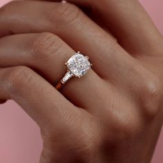 a woman's hand holding an engagement ring with a diamond in the center and side stones