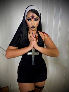 a woman dressed up as a nun holding a cross with blood all over her body