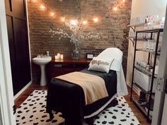 a spa room with a brick wall and lights on the ceiling, along with a black and white area rug