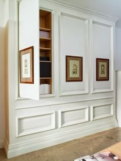 an empty room with white painted walls and framed pictures on the wall, along with bookshelves