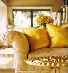 a living room filled with lots of furniture and yellow pillows on top of it's back