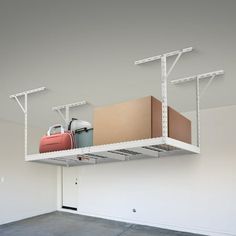 an overhead storage unit with two suitcases and luggage on the top shelf in a garage