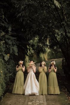 the bridesmaids are dressed in green dresses and holding bouquets on their heads