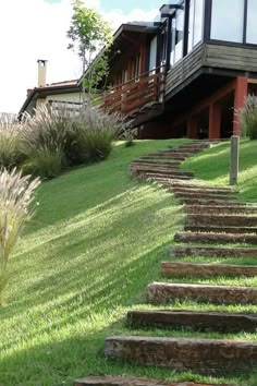 there is a house on the hill with stairs leading up to it and grass in front