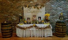 a table set up with sunflowers and wine barrels in front of a brick wall