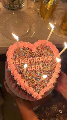 someone is holding a heart shaped cake with candles in the shape of a heart that says sagittamu baby